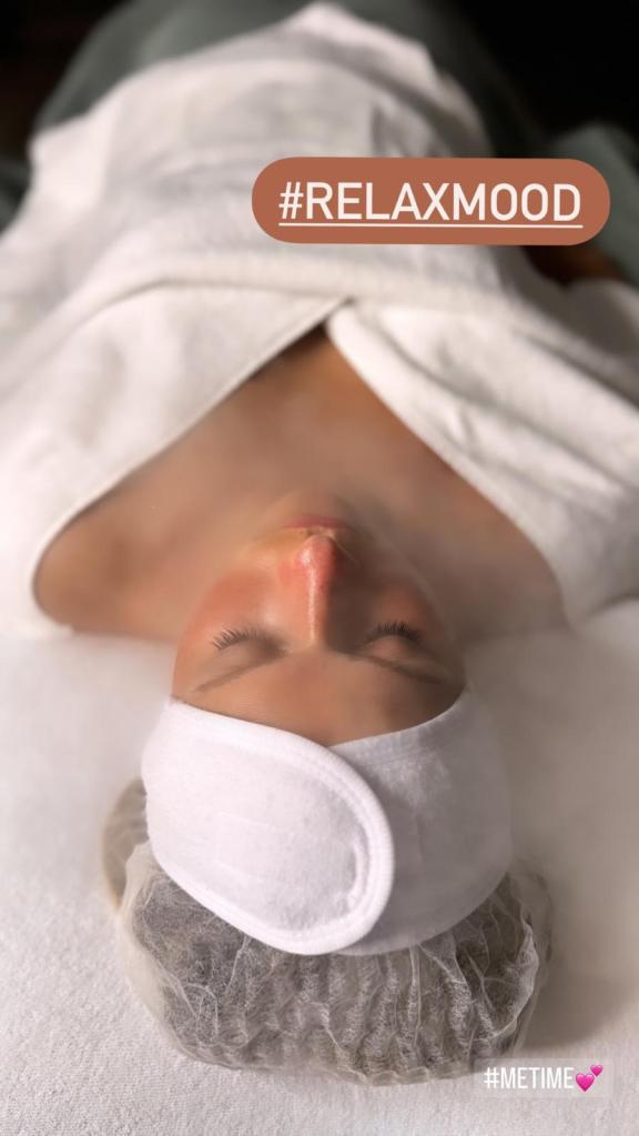 Eine Person liegt mit einem Handtuch über dem Körper und einem Stirnband auf einem Spa-Tisch und ist von Dampf umgeben, was ein Gefühl der Entspannung vermittelt.